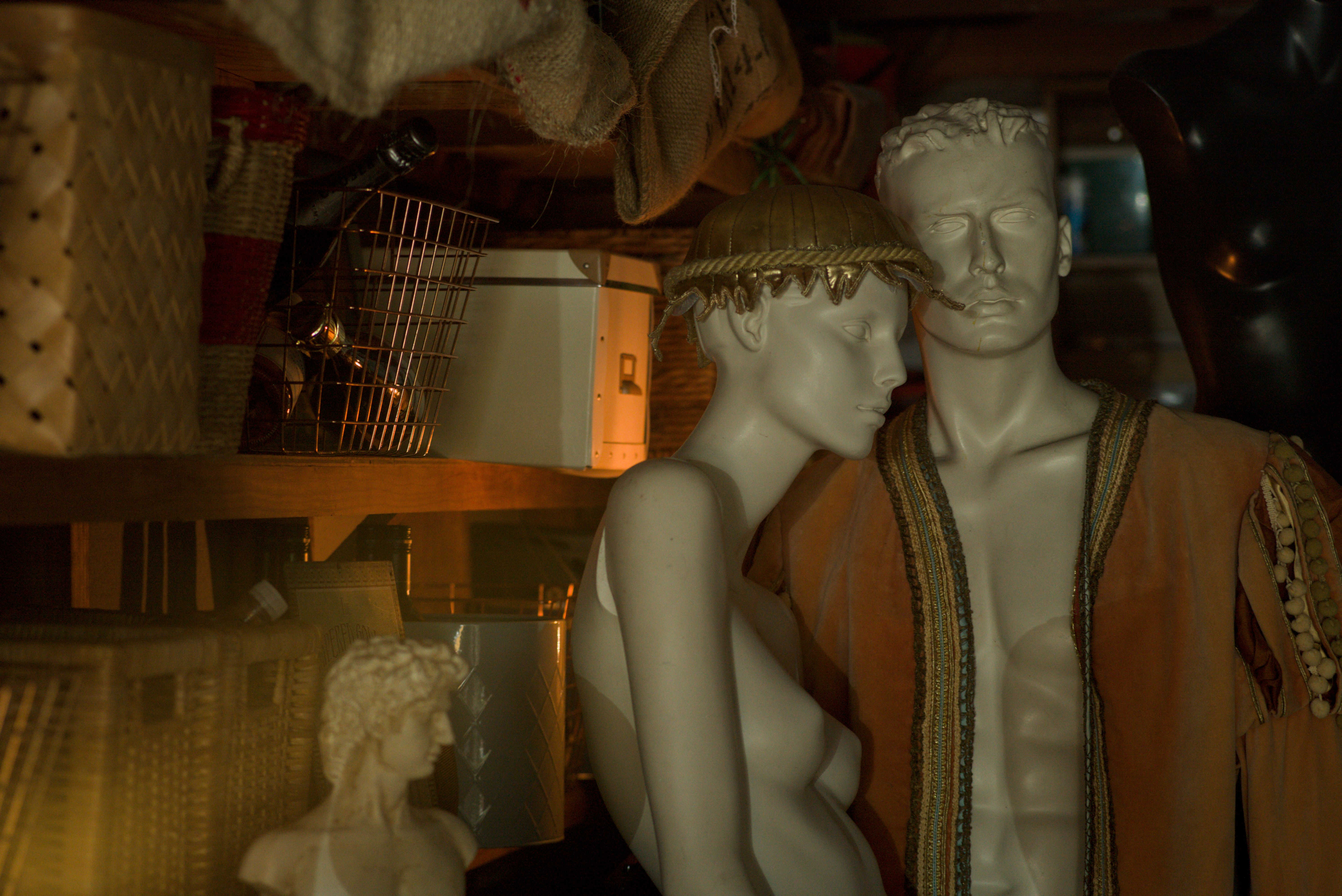 Beauty Everyday, 12: Dimly lit garage storage, featuring a male and female mannequin.