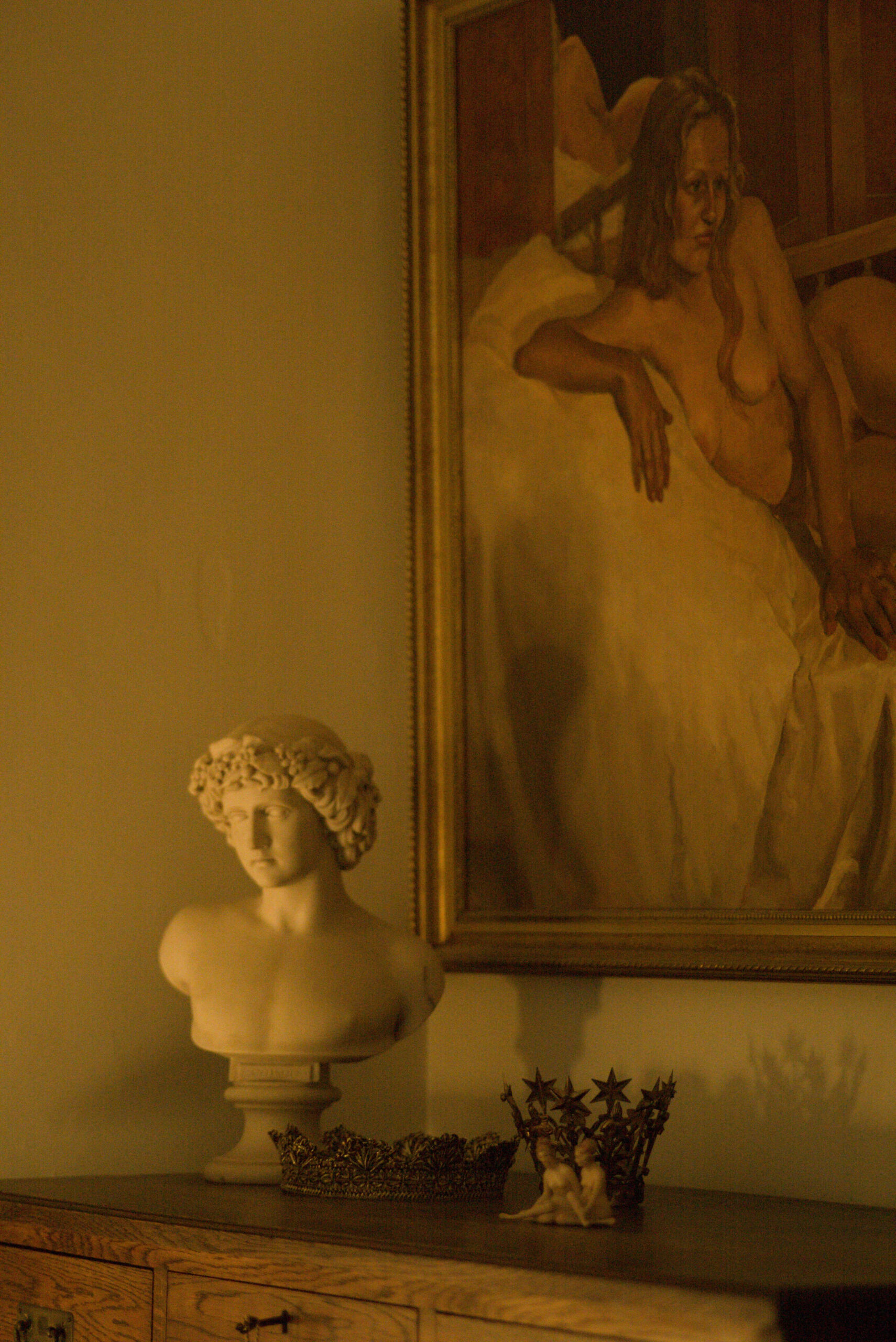 Beauty Everyday, 21: Interior wall with a framed portrait, over a classical bust, photographed under soft, indirect light.