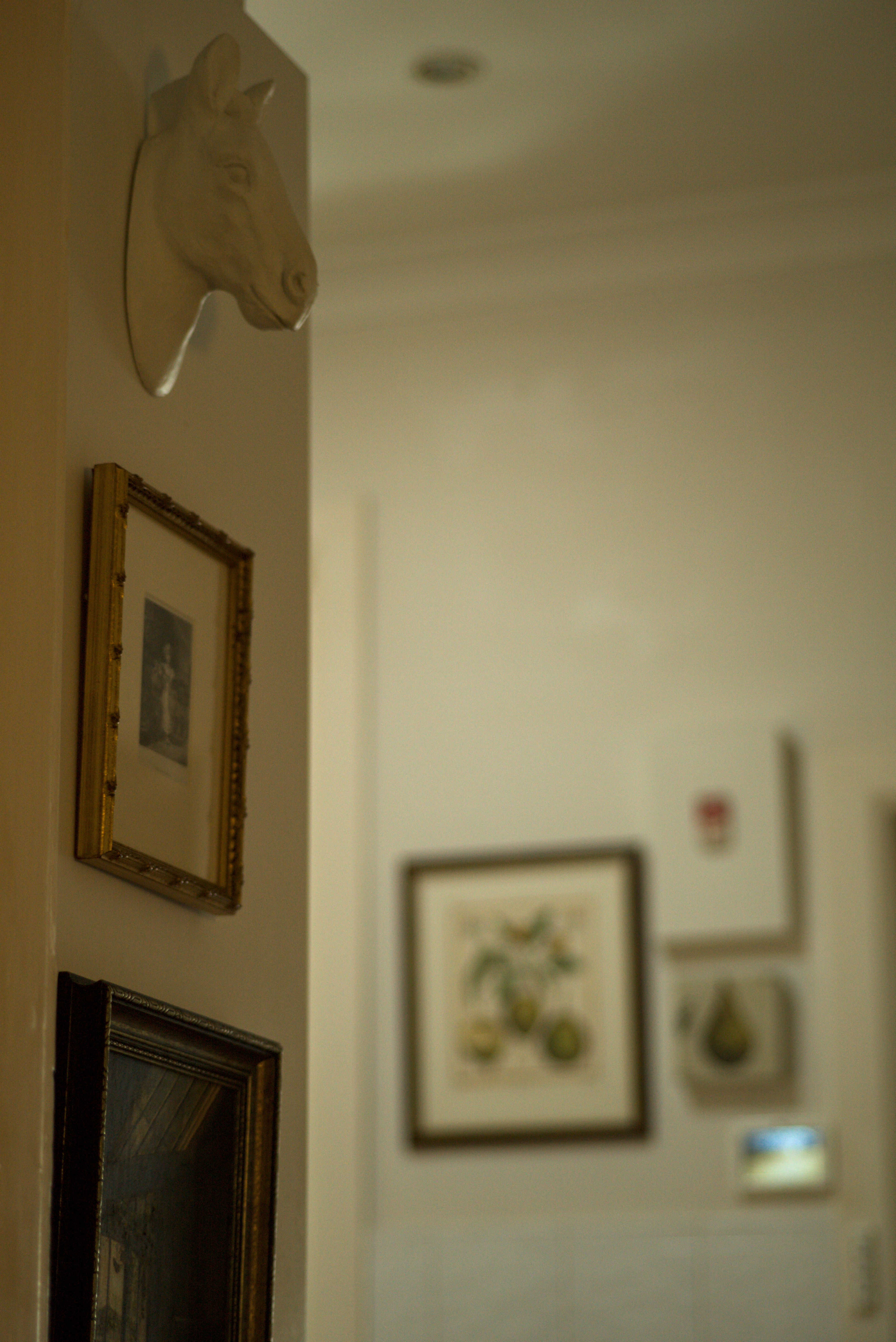 Beauty Everyday, 9: Close view of framed artwork above a light switch in a hallway with muted wall colour.