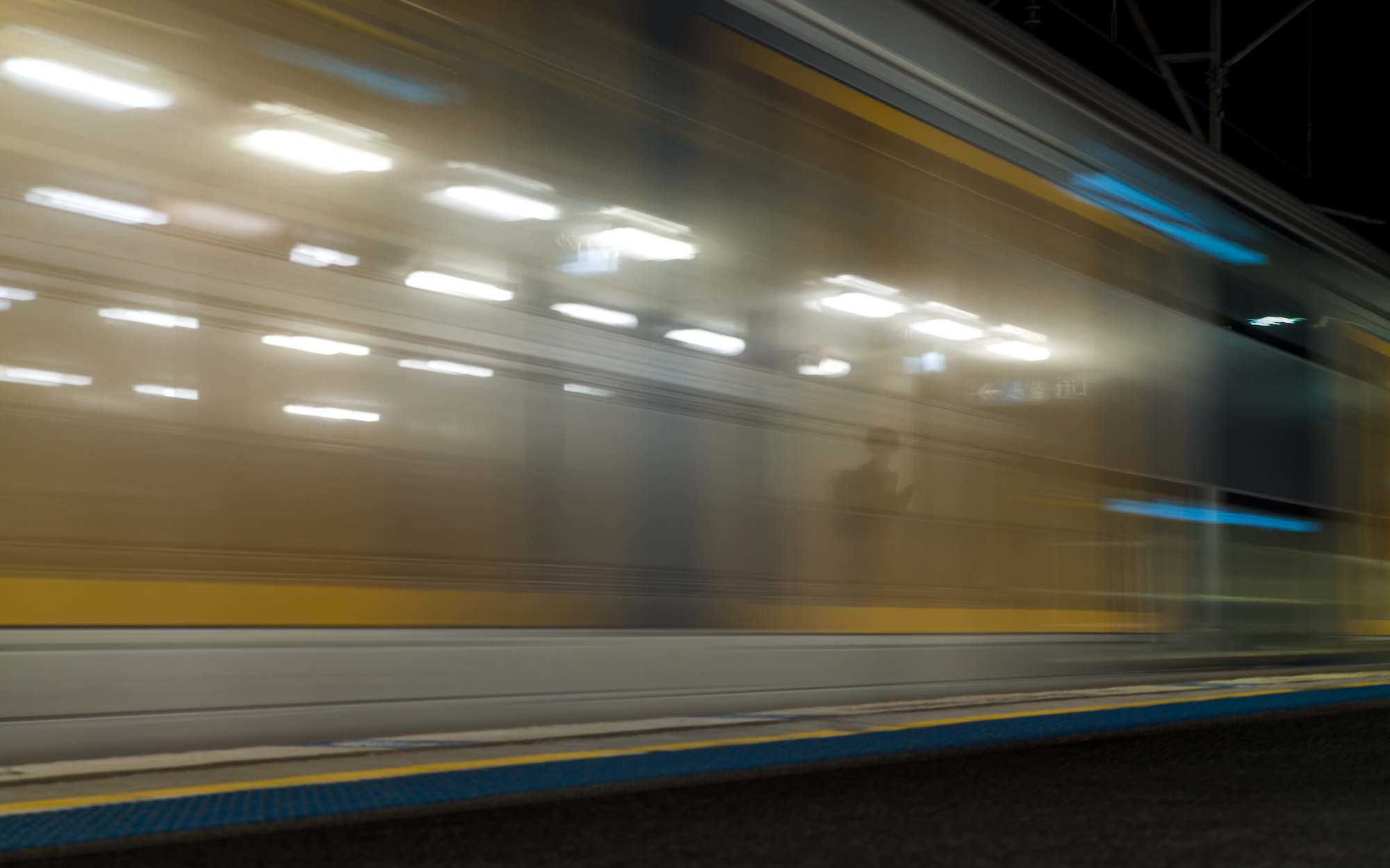 No Turning, 5 - Broadmeadow: Figure stands on opposite platform, silhouetted through fast-moving train.